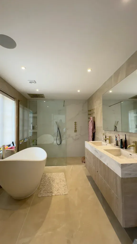 Renovated family bathroom in warm stone with freestanding bath